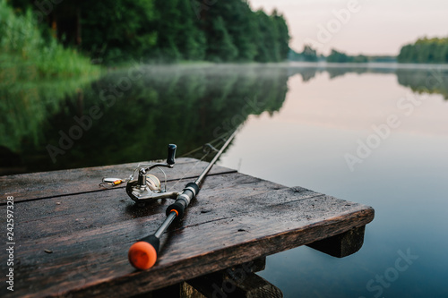 Foto Fishing rod, spinning reel on the background pier river bank