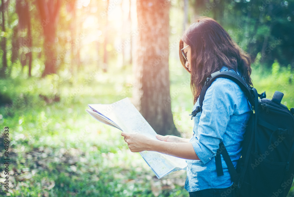 Obraz premium In tropical forest. Asian girls hikers She is holding a map and analysis of travel plans within the forest amid the hot weather and afternoon sun with copy space.