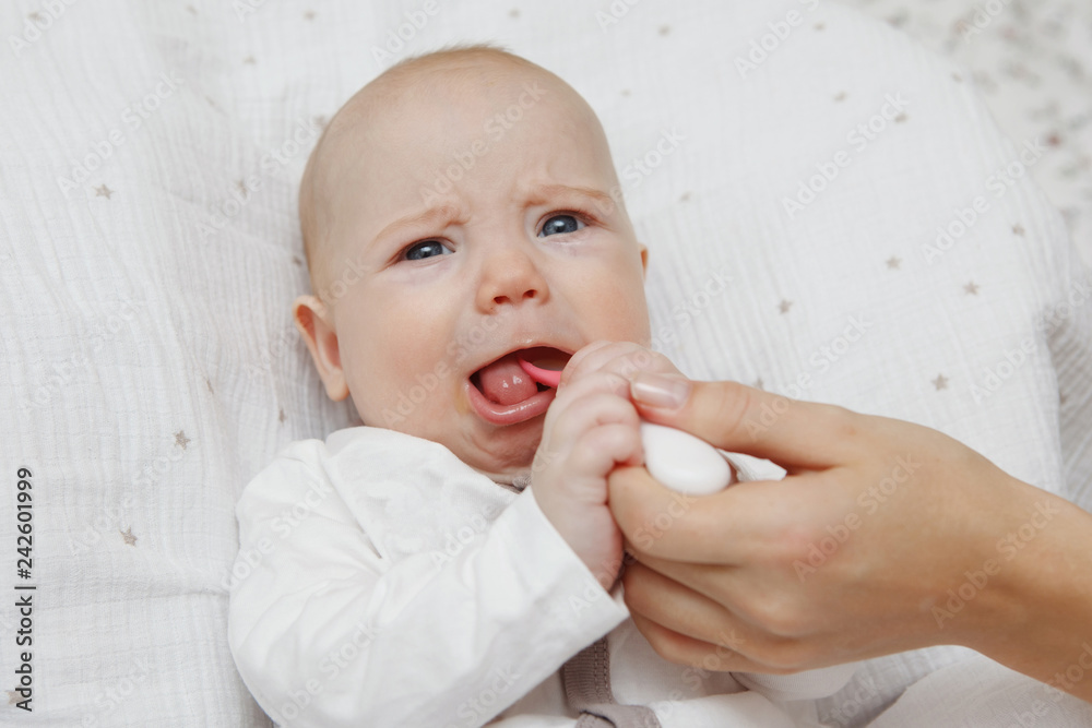 Beautiful lovely five-month girl eats with a spoon. On the face grimace of discontent. Healthy food. Maternal care. Childcare. Close-up. Beautiful lovely five-month girl eats with a spoon. On the face grimace of discontent. Healthy food. Maternal care. Childcare. Close-up.