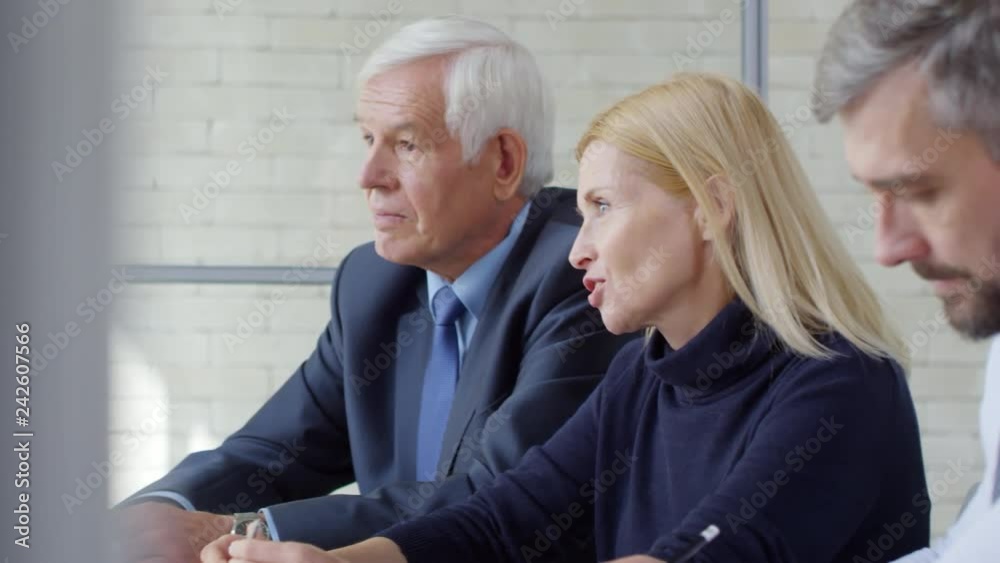 Tracking shot of group of businesspeople sitting at table and conducting panel job interview with cheerful Muslim woman in hijab Tracking shot of group of businesspeople sitting at table and conducting panel job interview with cheerful Muslim woman in hijab