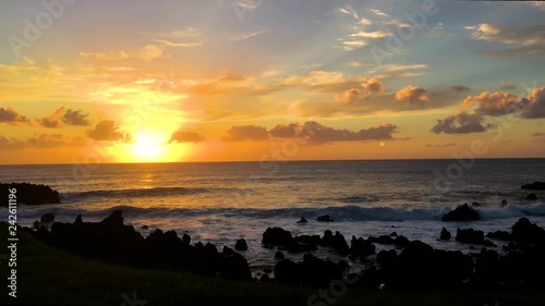 A sunset scene with warm yellow sky and big waves in Hanga Roa, Easter Island photo