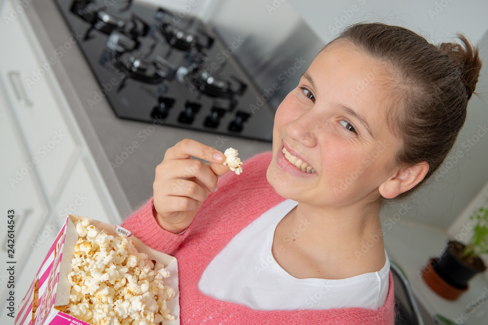 young teenage girl with pink sweater eating popcorn at home young teenage girl with pink sweater eating popcorn at home