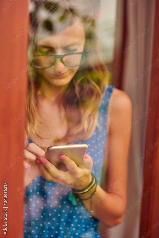 Young woman using smart phone indoors. Window reflection from outdoors. Young woman using smart phone indoors. Window reflection from outdoors.