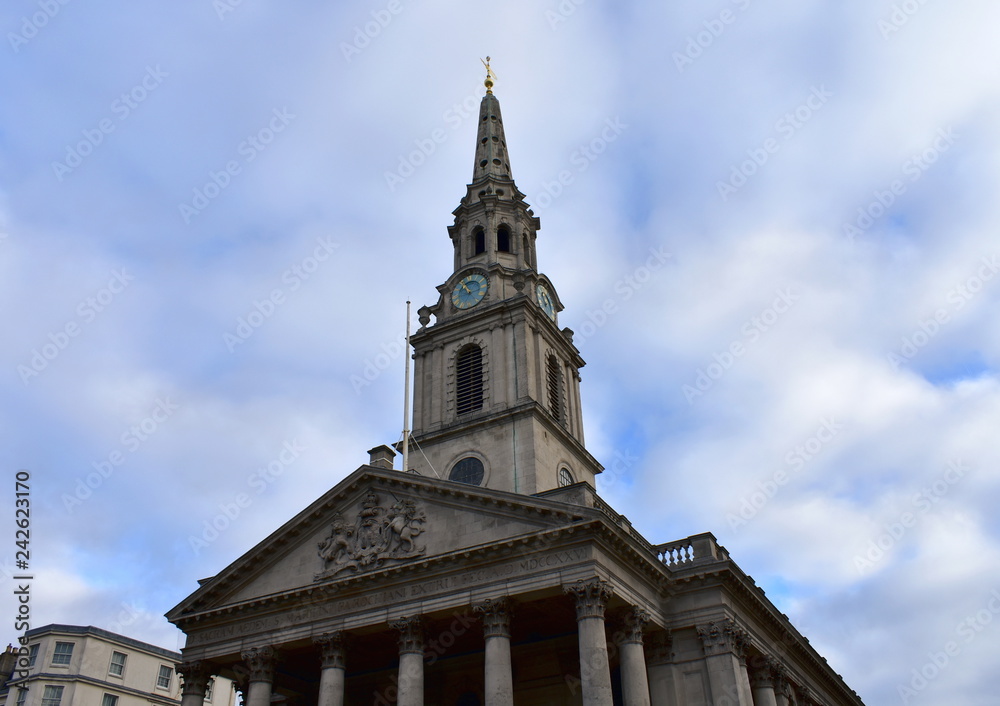 St Martin in the Fields church from Trafalgar Square. Neoclassical facade and tower with spire, blue and golden clock. London, United Kingdom.