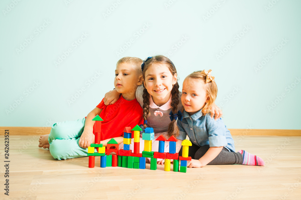 Fototapeta premium Happy smiling kids behind the wooden blocks castle