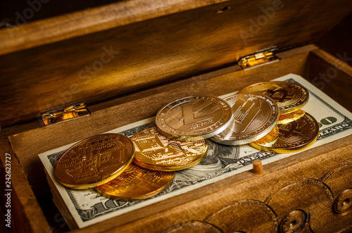 Cryptocurrencies in the form of coins on a pack of dollars in a wooden chest