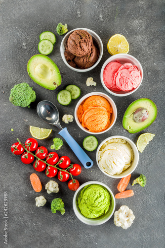 Trendy vegan food, summer healthy dessert concept, colorful diet vegetable ice cream with avocado, cucumber, tomato, beet, carrot, broccoli, cauliflower. Frozen veggie smoothie, black background