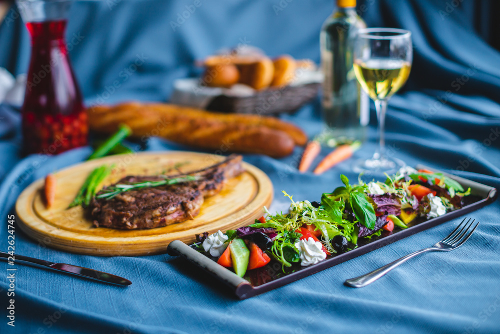 beef steak with salad, bread and wine on the table