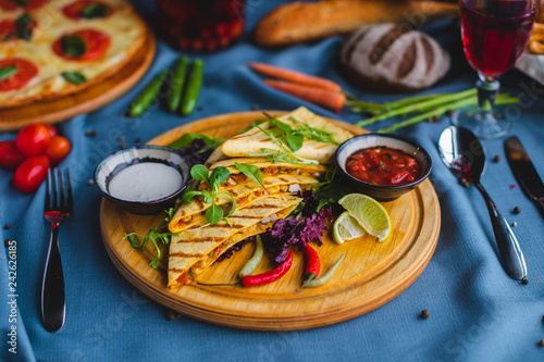 quesadilla with sauce and lemon on a wooden plate