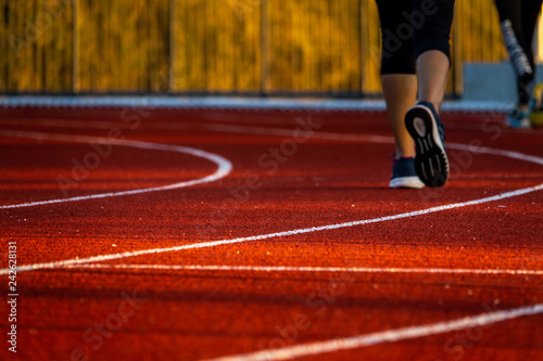 Red running track with runner's feet. Sport stadium for run.