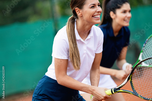 Happy fit people playing tennis together. Sport concept © NDABCREATIVITY