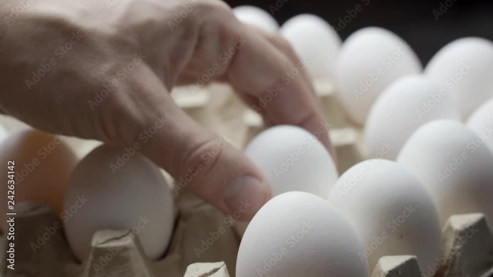 Close view of a farmer taking eggs from a pile and placing them into a carton to be sold