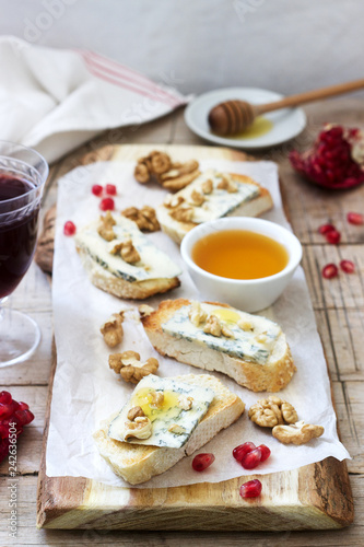 Sandwiches with blue cheese, pomegranate, honey and nuts served with red wine. Rustic style.