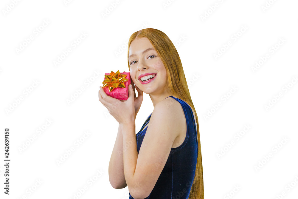 Attractive young red haired girl with a gift in hand near her face is smiling and looking into the camera on an isolated white background Attractive young red haired girl with a gift in hand near her face is smiling and looking into the camera on an isolated white background