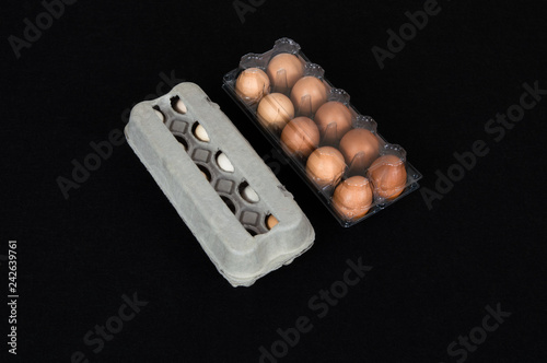 Twenty chicken eggs in carton and plastic boxes, isolated on black mat background