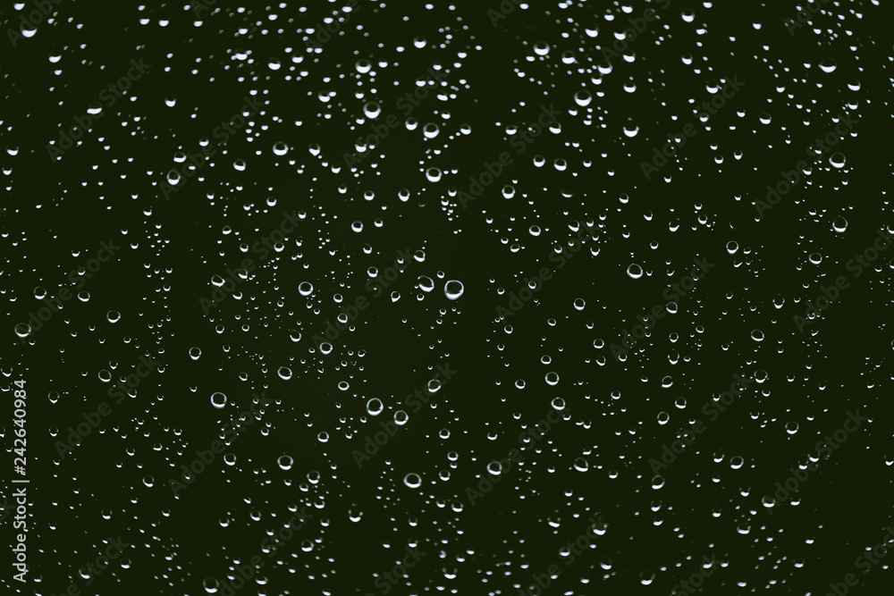 Dirty window glass with drops of rain. Atmospheric green background with raindrops. Droplets and stains close up. Detailed transparent texture in macro with copy space. Rainy weather. Dirty window glass with drops of rain. Atmospheric green background with raindrops. Droplets and stains close up. Detailed transparent texture in macro with copy space. Rainy weather.