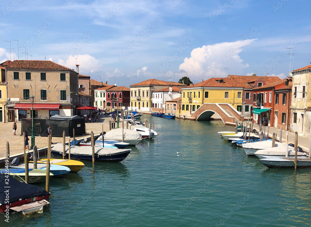 Sunny summer day in Murano, Venice, Italy, boats and colorful houses around. Venice panorama view 