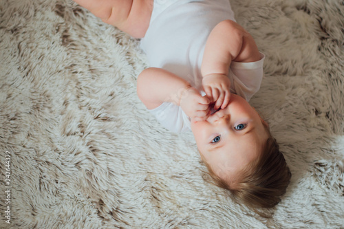Cute baby putting hands in mouth and sucking fingers