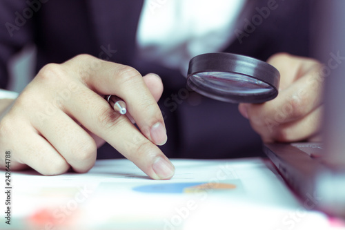 Businessman use a magnifying glass to analyze their sales. - Image 