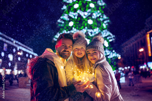 family, christmas, holidays, season and people concept - happy family over lights city background and snow at night