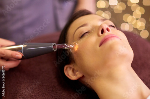 people, beauty, cosmetology and technology concept - beautiful young woman having needle free mesotherapy or hydradermie facial treatment by microcurrent firming device in spa photo