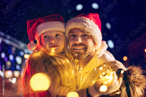 family, christmas, holidays, season and people concept - happy family over lights city background and snow at night