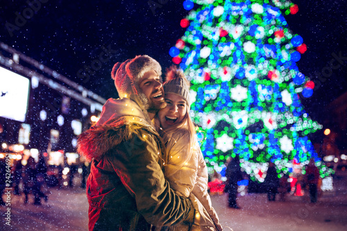 Adult couple hanging out in the city during Christmas time over lights city background and snow at night