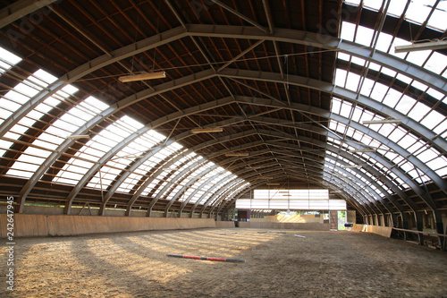 View in an empty indoor riding hall center for horses and riders. The riding school is suitable for dressage and jumping horses