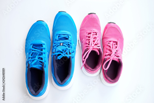 Pair of men's blue sneakers and pair of women's pink sneakers on white background.