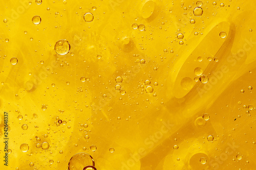 Abstract yellow background with oil drops and waves on water surface
