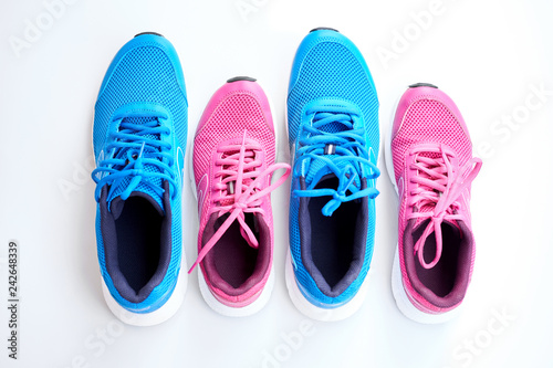 Pair of blue running sneakers for men and pair of pink one for women on white background.