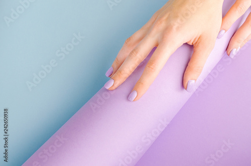 Hands with a purple manicure on a blue and purple background.