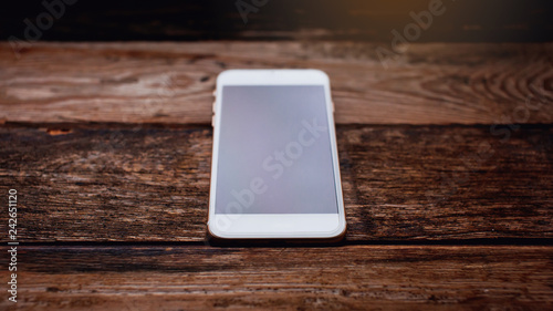 White phone with screen on the wooden background