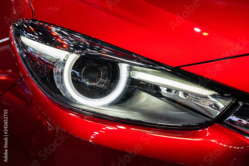 White headlight of red car with front hood and bumper © oppdowngalon