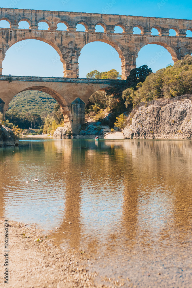 Transparent clear water of the Gardon River against the backdrop of the Roman aqueduct Pont du Gard