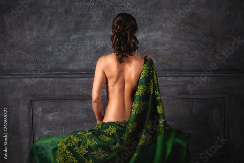 Beautiful girl with curls with a naked back. Back view