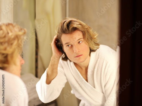 Applying the cream.young man looking in the mirror and combing his hair