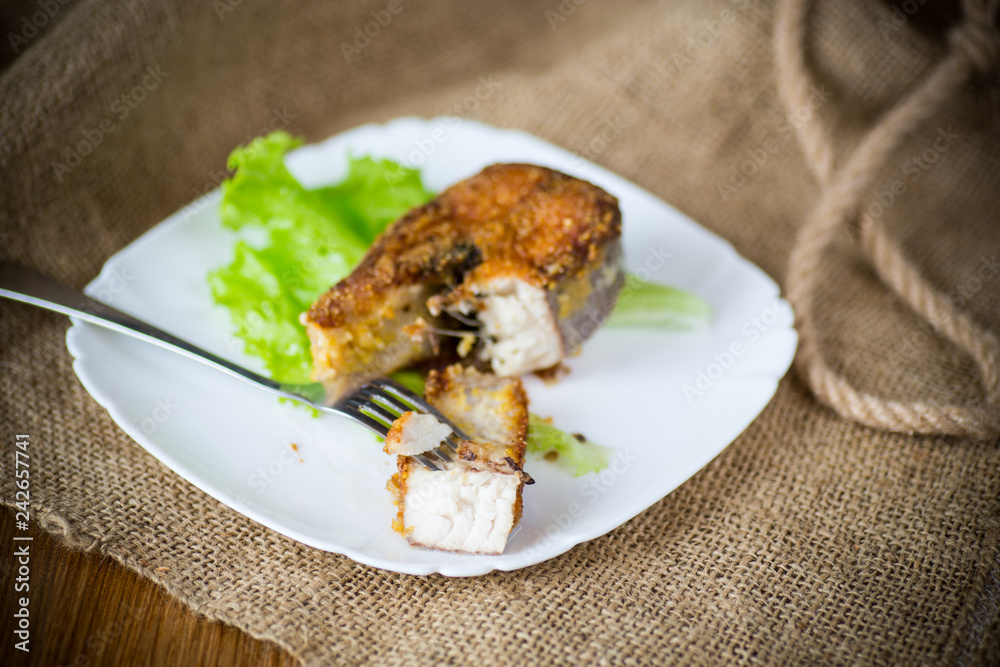 piece of fried pike fish in a plate on a wooden piece of fried pike fish in a plate on a wooden