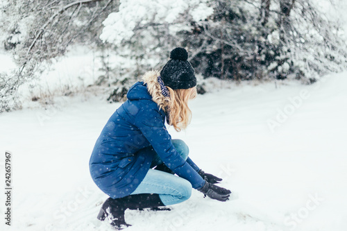 Fotografija Close-up of long-haired blonde laughing lady in knitted hat and scarf in snowy d