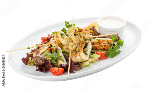 Squid grilled on skewers, with salad and sauce. On white background