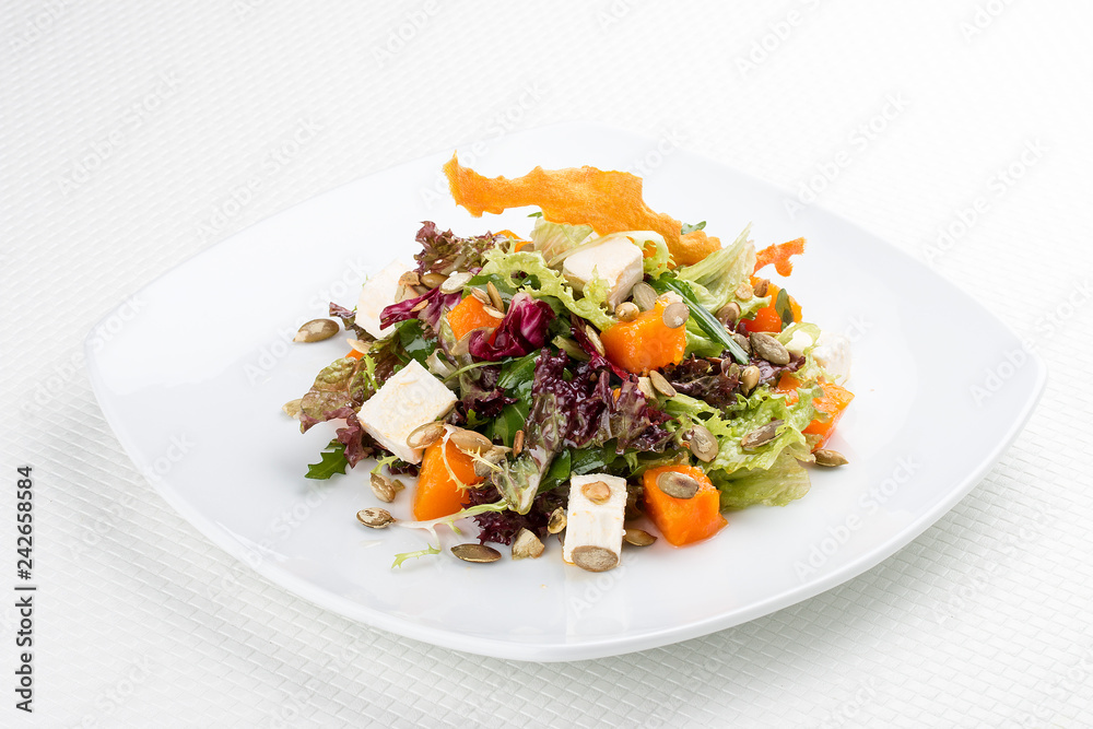 Salad with pumpkin and feta on a white background. Vegetarian