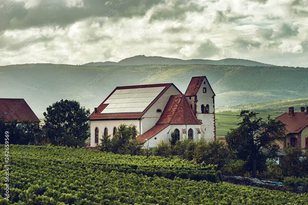 Obraz premium Photovoltaic panels on the church roof in Alsace, France. Religion and new technologies.