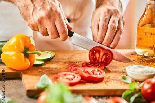 Chef cutting a fresh ripe red tomato