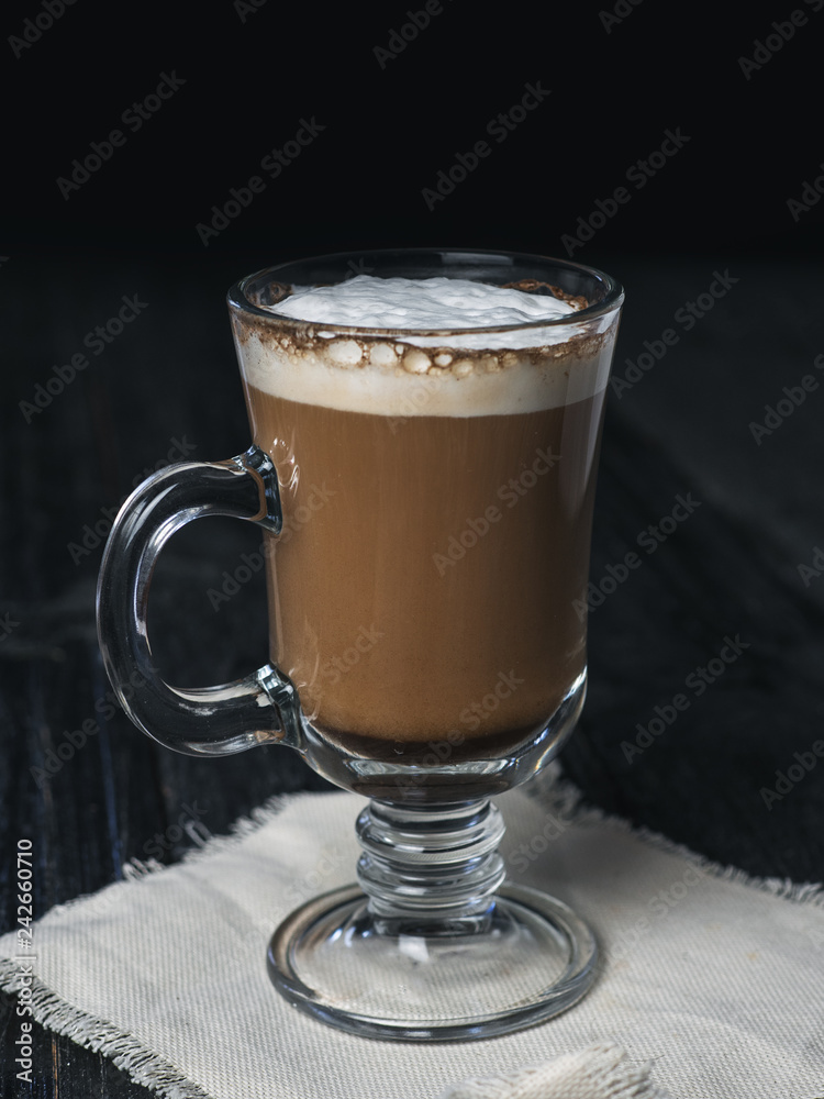 Irish coffee glass with foam and cinnamon on wooden table Irish coffee glass with foam and cinnamon on wooden table