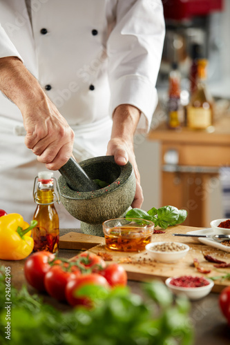 Chef grinding fresh herbs in a pestle and mortar