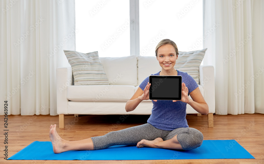 fitness, sport and healthy lifestyle concept - woman with tablet pc computer doing yoga exercises on mat at home fitness, sport and healthy lifestyle concept - woman with tablet pc computer doing yoga exercises on mat at home