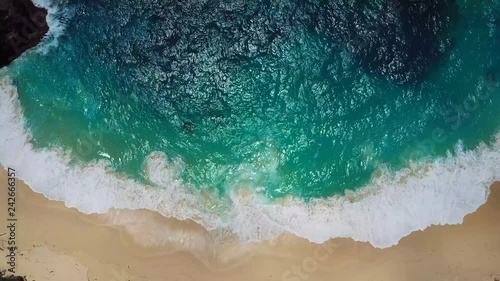 Beach scene, view from above - waves of turquoise ocean waters crashing on stones. Kelingking beach, Nusa Penida. 4k footage.