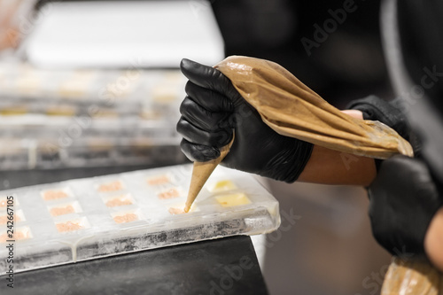Fotografija production, cooking and people concept - confectioner with pastry bag squeezing