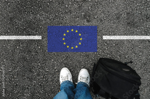 Photography a man with a shoes and backpack is standing on asphalt next to flag of European