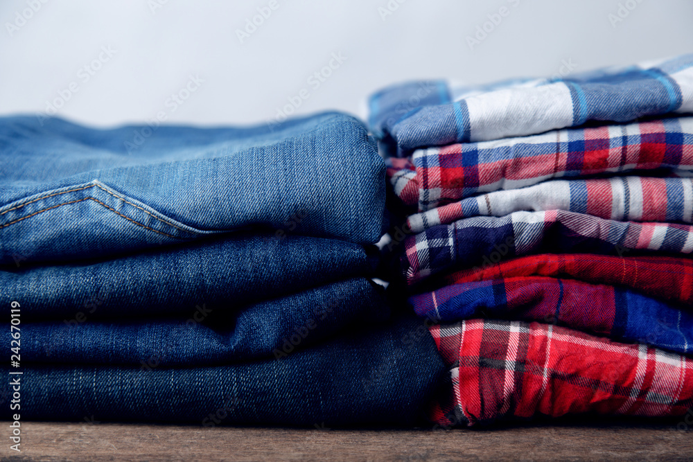 checkered shirts and jeans stack on wooden background